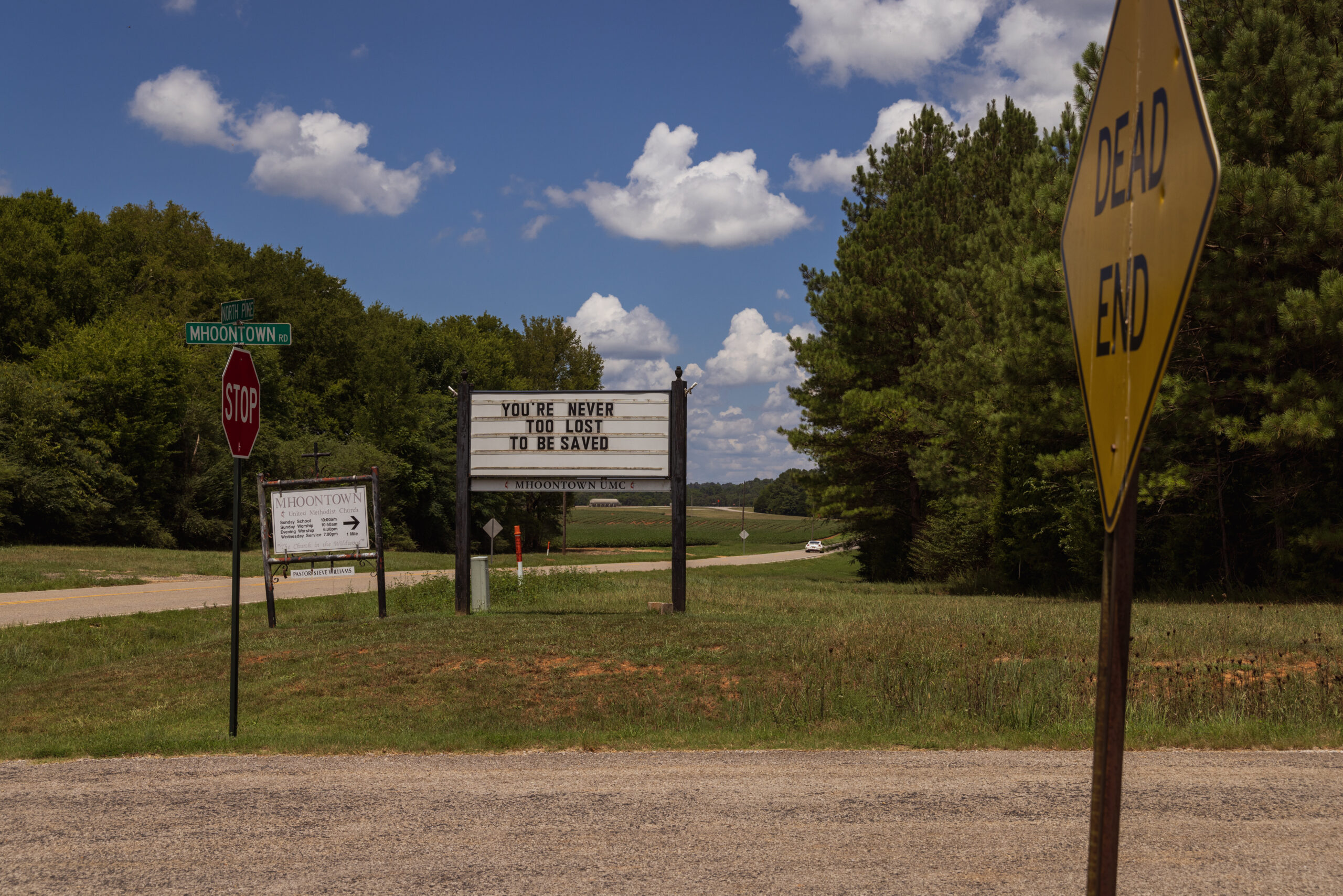 A church sign on a dirt road.